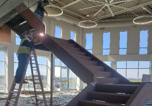 man installing a metal staircase in a commercial building